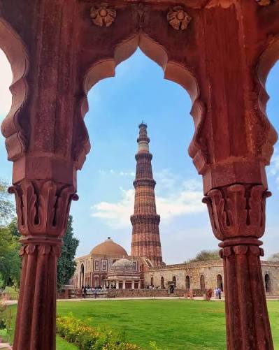 Qutub Minar framed by red sandstone arches